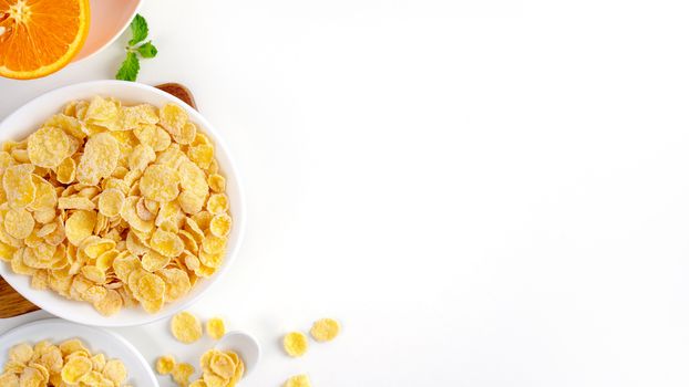 Top view of corn flakes bowl sweeties with milk and orange on white background, flat lay overhead layout, fresh and healthy breakfast design concept.