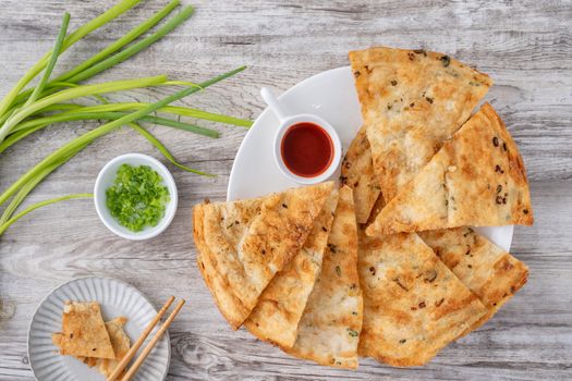 Taiwanese food - delicious flaky scallion pie pancakes on bright wooden table background, traditional snack in Taiwan, top view.