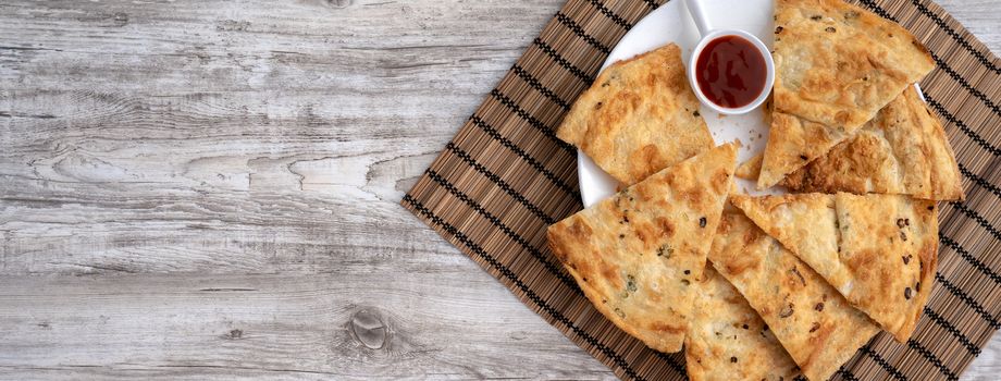 Taiwanese food - delicious flaky scallion pie pancakes on bright wooden table background, traditional snack in Taiwan, top view.