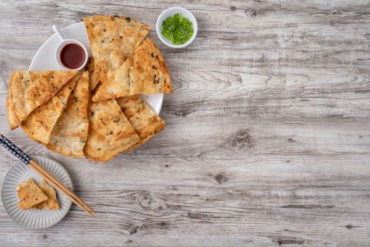 Taiwanese food - delicious flaky scallion pie pancakes on bright wooden table background, traditional snack in Taiwan, top view.