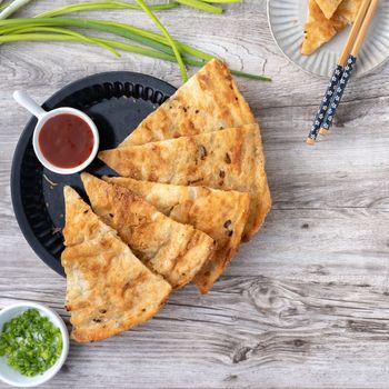 Taiwanese food - delicious flaky scallion pie pancakes on bright wooden table background, traditional snack in Taiwan, top view.