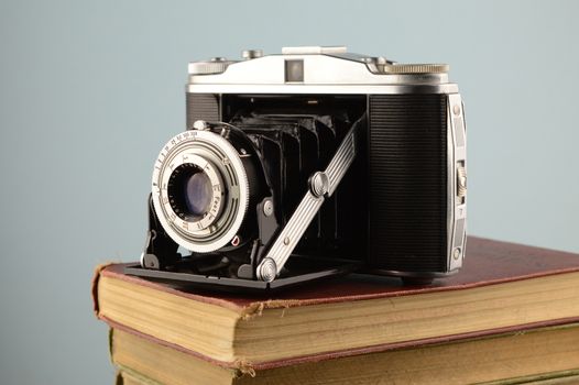 A vintage camera resting on a stack of old books.