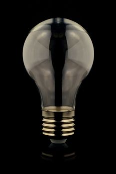 An isolated over black reflective surface image of a lightbulb with an empty inside which is good for graphic design insert composites.