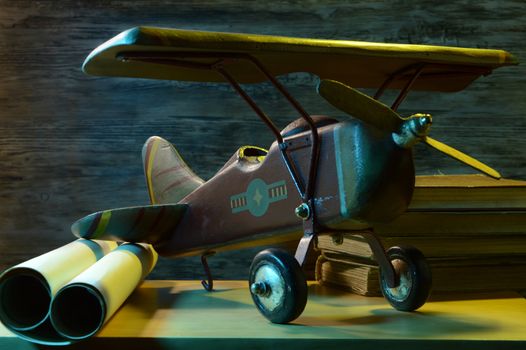 A small wooden airplane rests on a childs bedroom shelf with some colored lights to accent the scene.