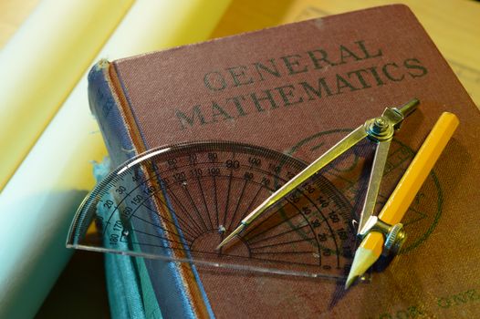 A closeup of a general mathematics school book and a compass and protractor.