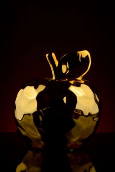 A vertical image of a single golden apple with a deep red and black gradient background.