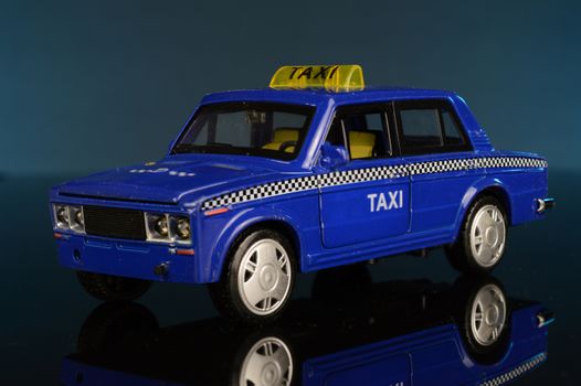 A whole front view of a blue taxi cab model car over a blue background.