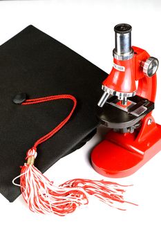 A grad hat and microscope over a white background.