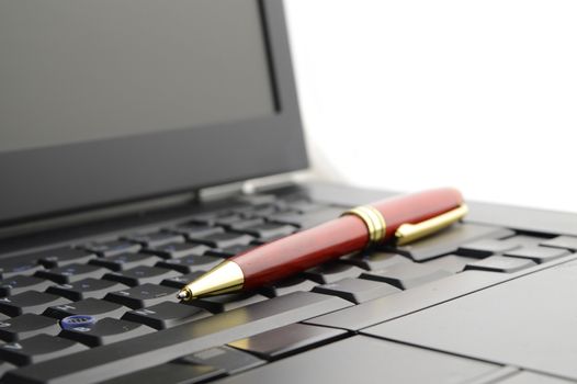 A closeup of a business pen and laptop for the work day representation.