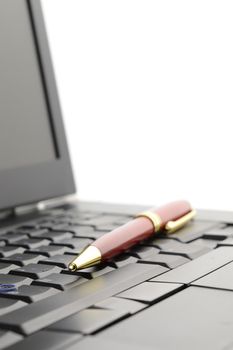 A closeup of a business pen and laptop for the work day representation.