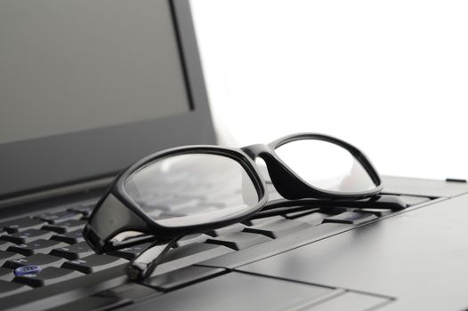 A pair of reading glasses set on a laptop for better screen viewing.