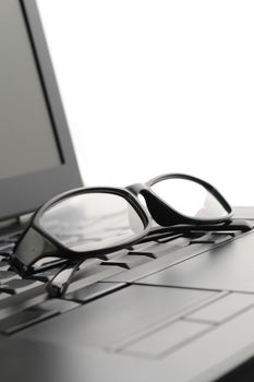 A pair of reading glasses set on a laptop for better screen viewing.