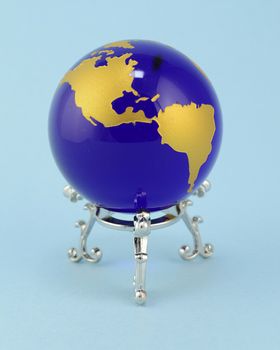 The Globe of Earth with a silver stand over blue background.