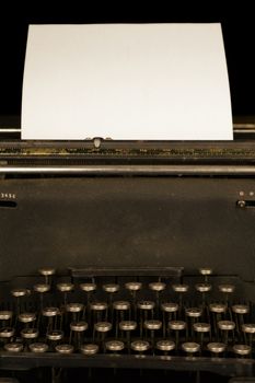 A closeup view of an antique typewriter machine from the mid 1900s with a blank piece of paper.