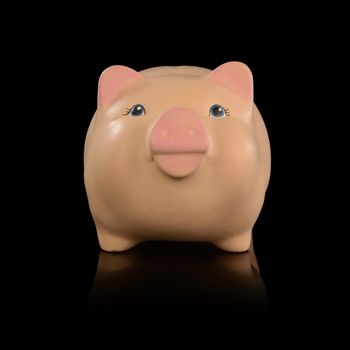 An isolated over black reflective surface image of a pink piggy bank for saving coin money.