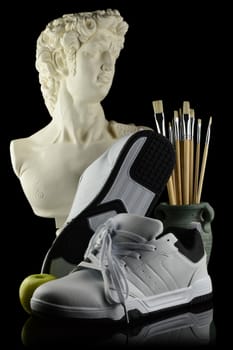 A styled pair of mens white shoes in an artistic setting.