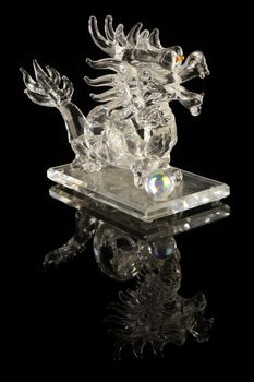 A lucky crystal dragon over a black reflective background.