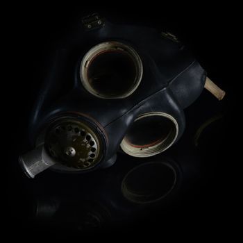 A vintage military grade gas mask left in a dark area.