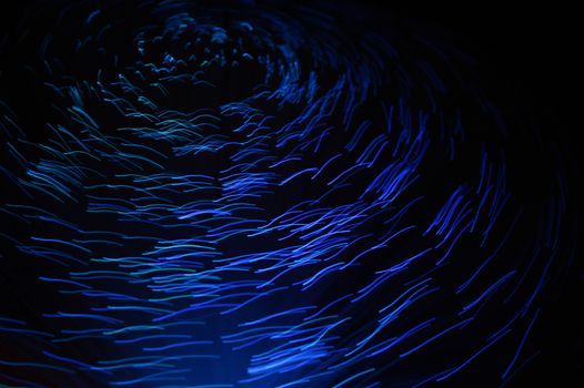 An abstract blue spiral of blurred lights over a dark background.