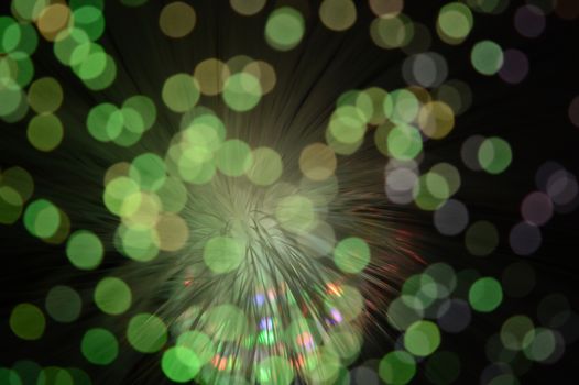 A bokeh focused image of some fiber optic cables with lights shining through them.