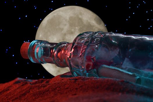 A closeup low angle shot of a message in a bottle revealed in the sandy shoreline during the night time light.