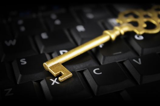 A shiny brass key rests on top of a computer keypad for conceptualizing security issues in the modern cyberspace digital age.