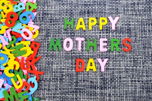 A childish creation of writing a Happy Mothers Day message using wooden alphabet letters.