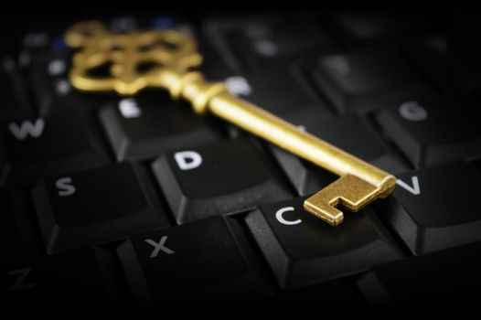 A shiny brass key rests on top of a computer keypad for conceptualizing security issues in the modern cyberspace digital age.