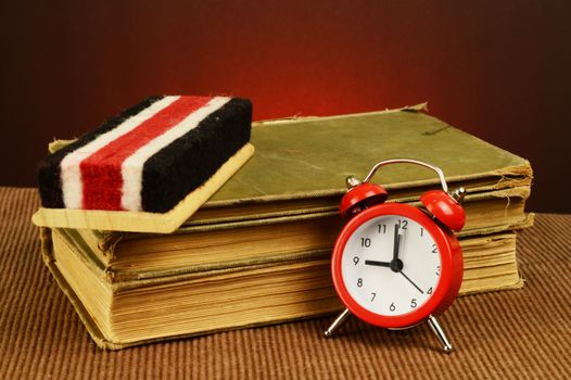An old stack of books with a chalk eraser and alarm clock made to have a historical feeling.