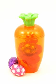 Some festive ways to store Easter candy inside a cute carrot container isolated over white.