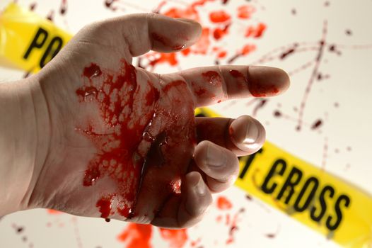 Closeup of a victim at a crime scene with bloody hands.