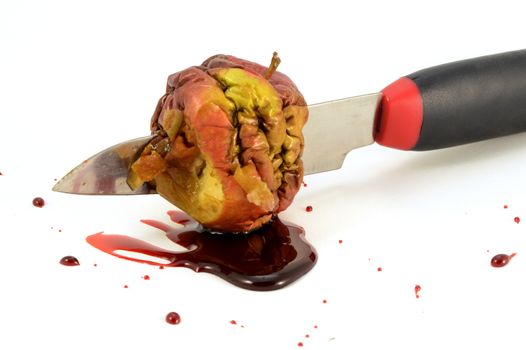 A closeup of one bad apple with a bloody knife wound.
