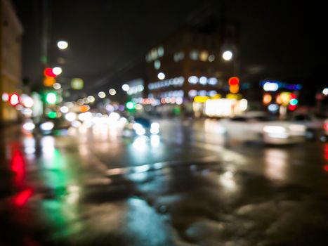 defocused night rain city street view with cars crossing road.