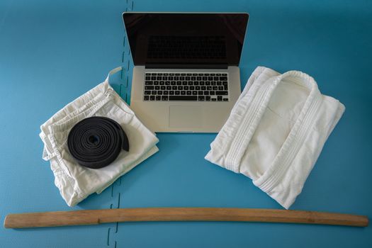 Martial art aikido uniform on a tatami with notebook for on line training and boken.