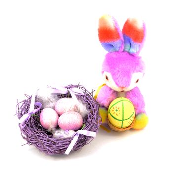 An isolated over white image of a cute plush Easter Bunny and a festive purple nest with eggs for the holiday season.