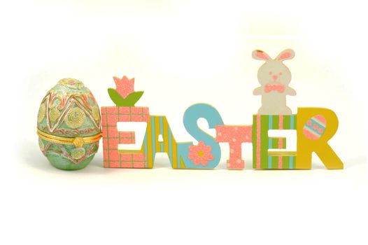 A colorful Easter cutout sign next to a decorative hollow egg isolated over a white background for the holiday season.