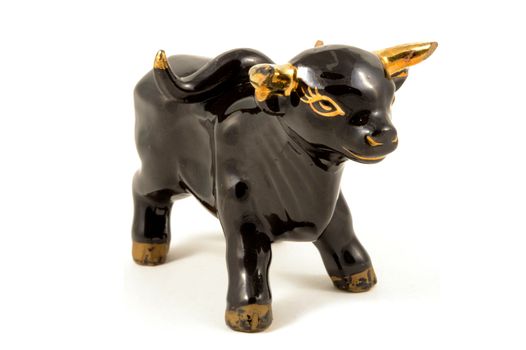 An isolated over a white background image of a side view porcelain black bull with gold highlights.