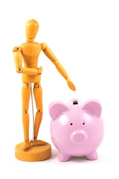 An artists wood dummy and a piggy bank are isolated over a white background for money related concepts.