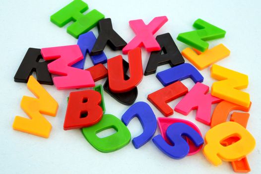 A closeup of many colorful alphabet learning pieces with a small magnet on the back for kids use around the kitchen appliances.