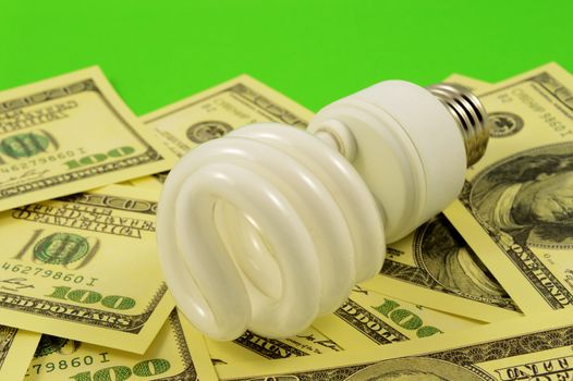 A closeup image conceptualizing American money and a CFL bulb for the eco friendly energy saving method.