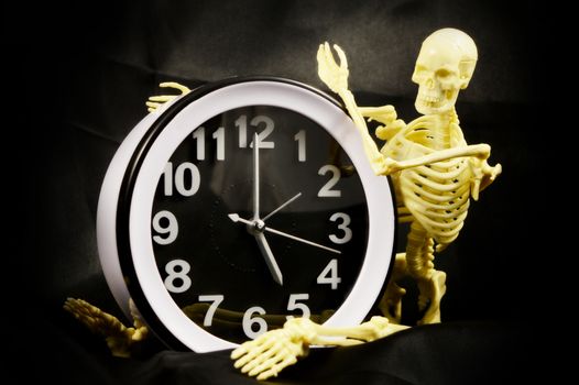 A conceptual image of being worked to the bone using a five pm time clock and a human skeleton.