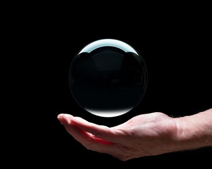Senior caucasian hand holding a crystal futures or fortune telling ball with black center to suggest holding future in your palm