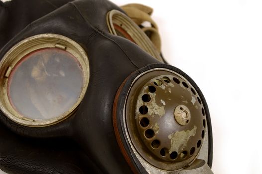 A closeup view of an antique Military grade gas mask over a white background with wear and tear distinguishing its age and vintage.