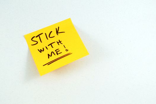 A pun playing with the written words STICK WITH ME on top of a yellow sticky note making the office a little less stressful after reading.