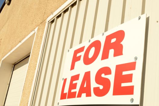Closeup view of a large sign displaying the words for lease on the exterior of a commercial building.