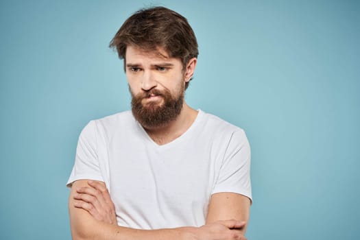 Man in white t-shirt lifestyle studio emotions facial expression blue isolated background. High quality photo