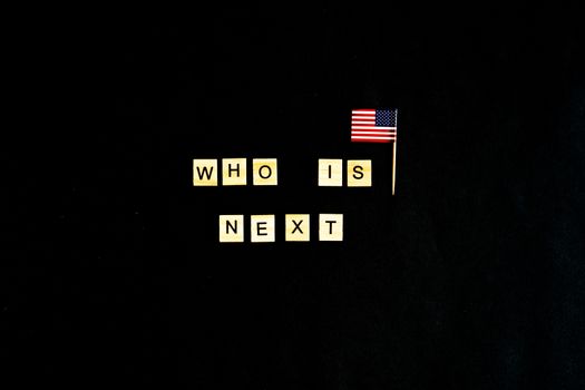 The phrase Who is the next American President - with an American flag in the background. A new election race in the United States. Primary. Candidates. Politics. Government. Force. flatlay, top view.