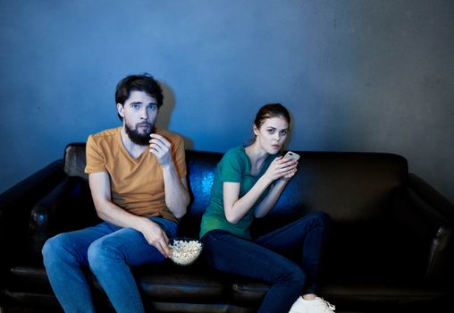 A man and a woman are watching a movie in the cinema on the sofa indoors. High quality photo
