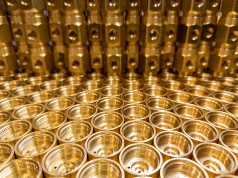 an abstract industrial close-up background of shiny brass metal threaded hexagonal fitting parts.