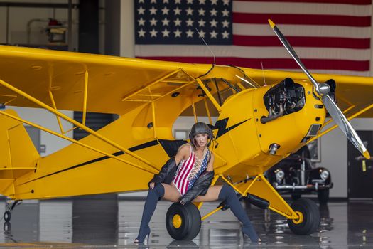 A beautiful blonde model poses with a vintage WWII aircraft